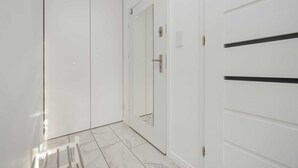A hallway with white doors, a mirrored closet door, and a tiled floor.
