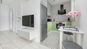 A modern kitchen with a built-in TV, a refrigerator, and a dining area with a table and chairs.