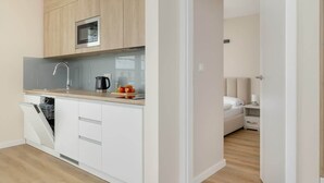 Una cocina moderna con armarios blancos, microondas y lavavajillas.