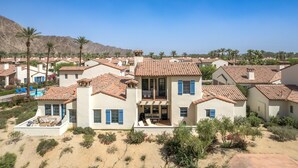 A residential area with multiple houses featuring red-tiled roofs and white walls, surrounded by palm trees and a mountainous backdrop. - Newly Renovated! Designer Chic 2-Story Townhome, Views, Private Patio, Garage, Pet Friendly! (L97) (La Quinta)