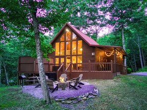 Une cabane dotée d’une terrasse, d’un foyer extérieur et de meubles de jardin.
