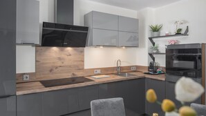 A modern kitchen with grey cabinets, a wooden countertop, a black range hood, and a built-in oven. - Lovely apartment in Micetici (Micetici)