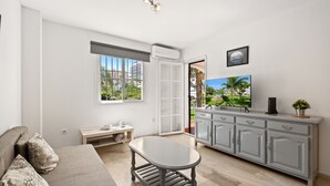 A modern living room with a sofa, a table, a TV, and a view of a balcony with a cityscape. - Benalmar Beach, nearby amenities (Benalmádena)