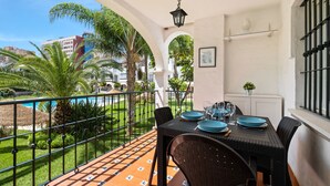 A terrace with a table set for dining, surrounded by a white wall and a black railing. - Benalmar Beach, nearby amenities (Benalmádena)