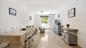 A modern kitchen with a dining area, featuring a table with chairs, a small island, and a view through the window. - Benalmar Beach, nearby amenities (Benalmádena)