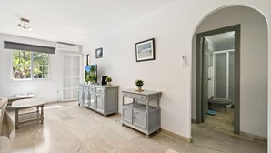 A spacious room with a large window, a dining table, a grey cabinet, and a doorway leading to a bathroom. - Benalmar Beach, nearby amenities (Benalmádena)