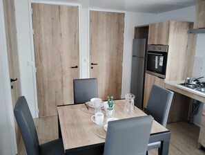 A modern kitchen with wooden cabinets, a stainless steel refrigerator, and a gas stove.