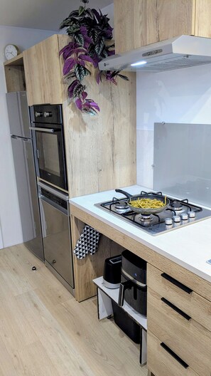 A modern kitchen with a built-in oven, a gas stove, and a microwave.