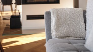 A modern living room with a grey sofa, a white throw pillow, and a black-framed television.