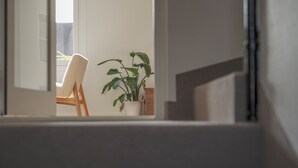 A staircase leading to a room with a chair and a potted plant.