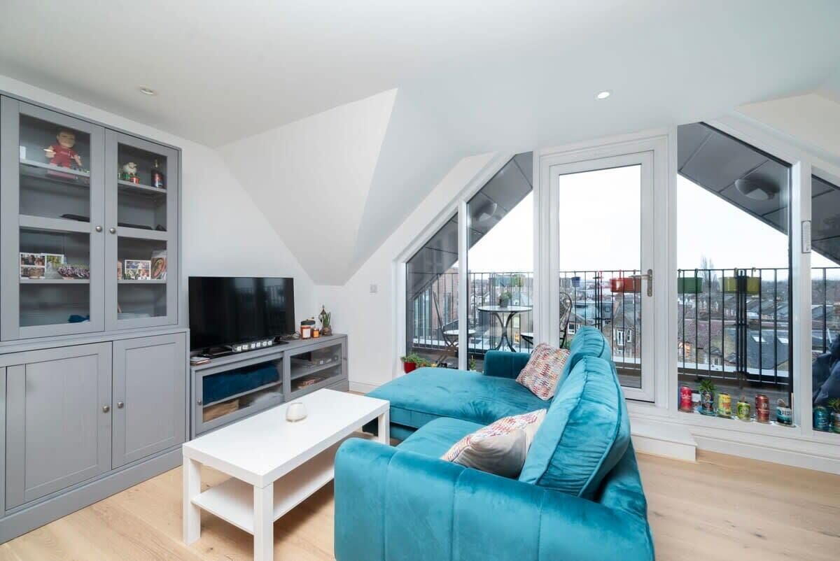 A modern living room with a teal sofa, a flat-screen TV, and a white coffee table.