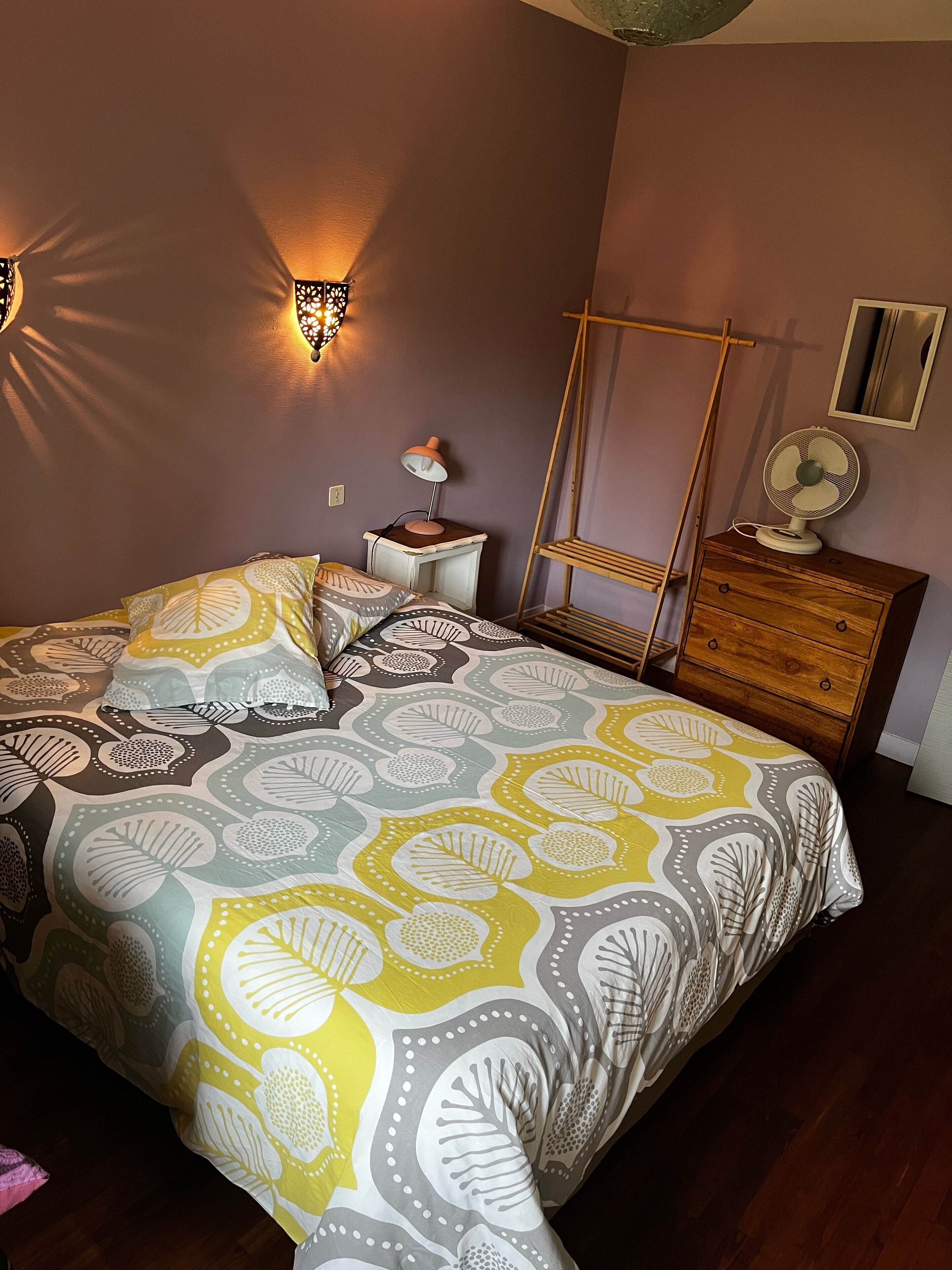 A bedroom with a bed, bedside tables, a hanging chair, and a dresser.