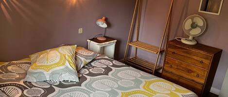 A bedroom with a bed, bedside tables, a hanging chair, and a dresser.