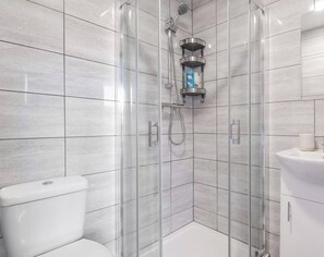 Ein modernes Badezimmer mit einer gläsernen Duschkabine, einer Toilette und einem Waschbecken.