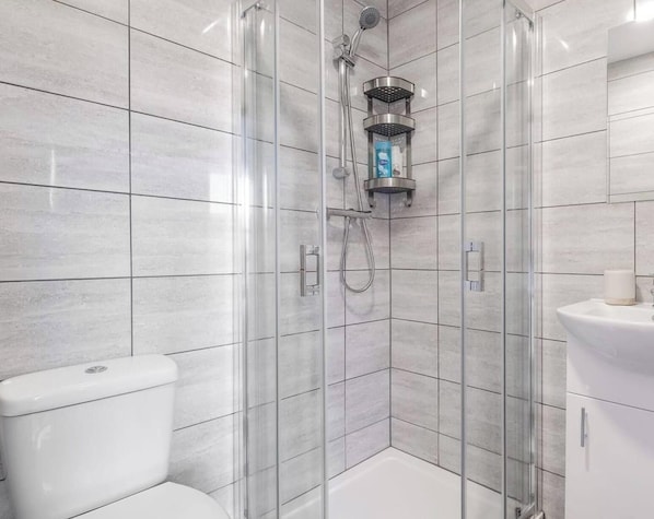 A modern bathroom with a glass-enclosed shower, a toilet, and a sink.