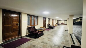 A hallway with a reception desk, seating area, and a staircase leading to an upper level. - The Tendo Inn (Pollachi)