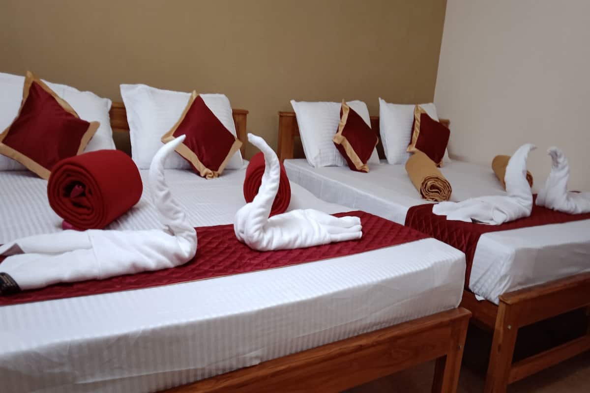 Habitación de hotel con dos camas de madera, cada una con almohada roja y blanca, y una manta roja.