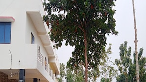 A two-story building with a balcony, surrounded by greenery and trees. - GP Village Resort (Melmalayanur)