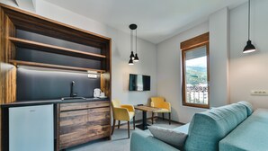 A compact living space with a kitchenette, a sofa, a dining area, and a window with a view. - Hotel Vladimir (Budva)