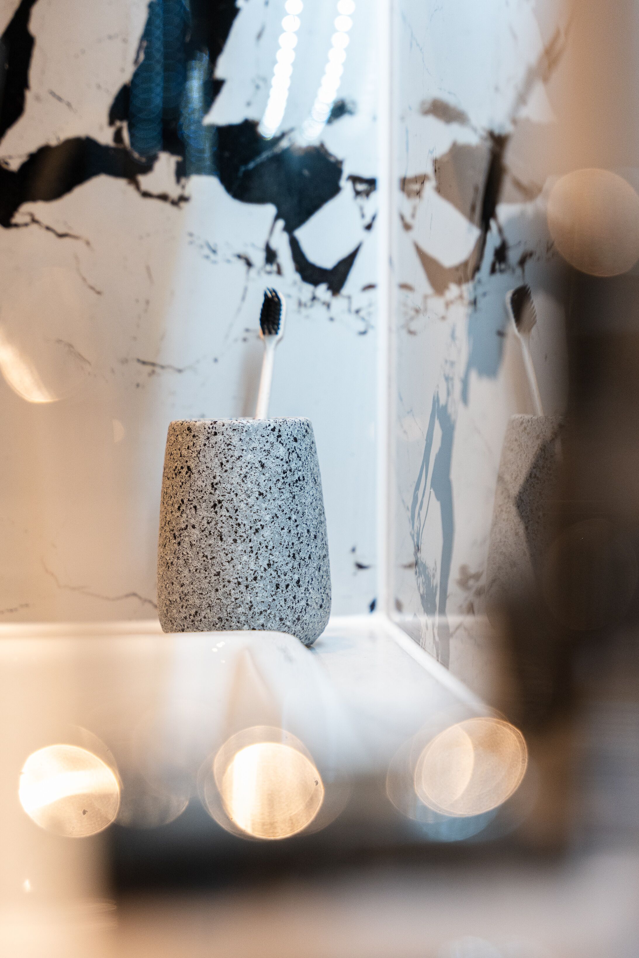 A modern interior with a textured wall, a speckled vase, and a reflective surface.