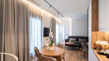 Una habitación de hotel moderna con zona de comedor, sofá y un muro decorativo de madera.