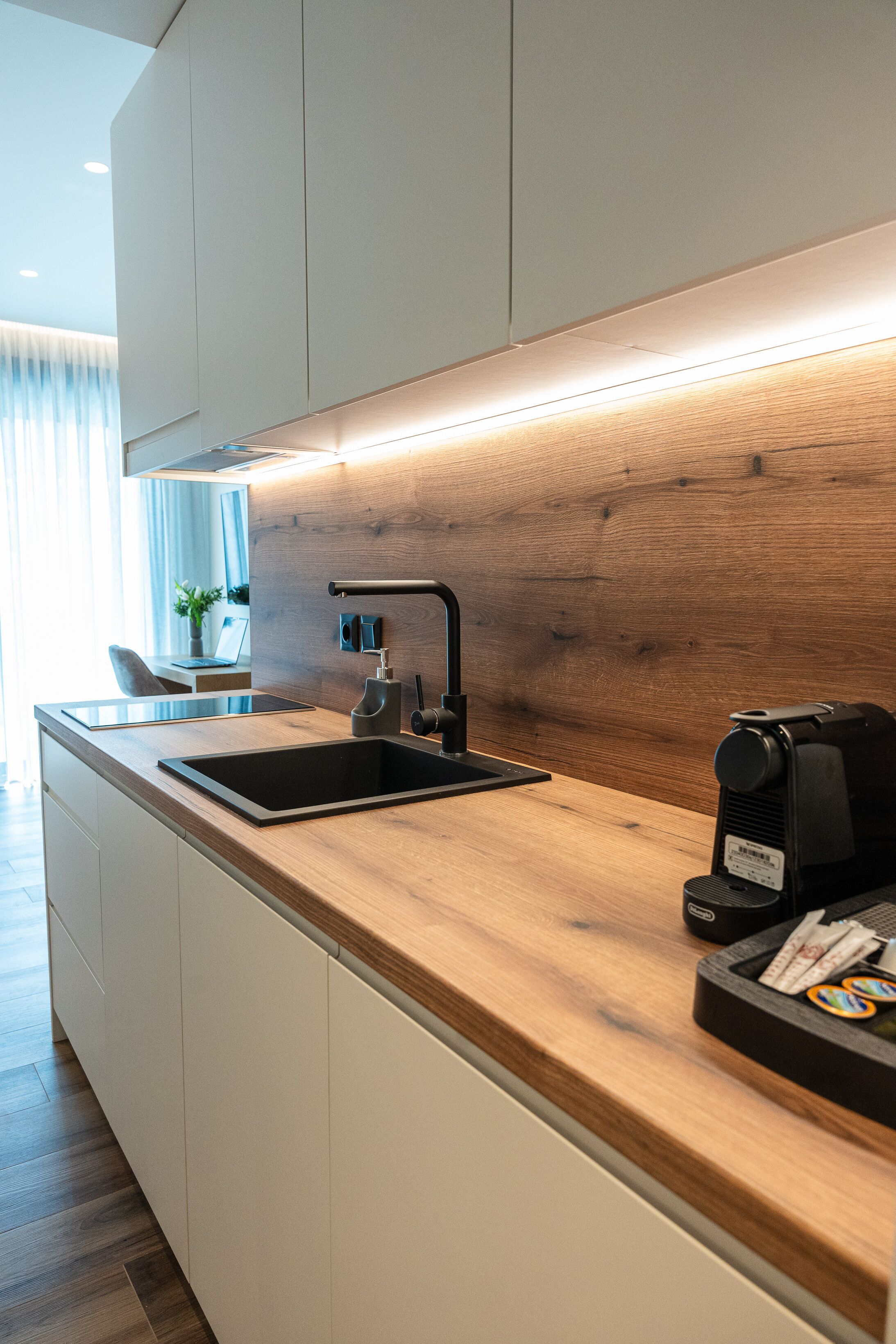 Une cuisine moderne avec un plan de travail en bois, un évier noir et une machine à café.