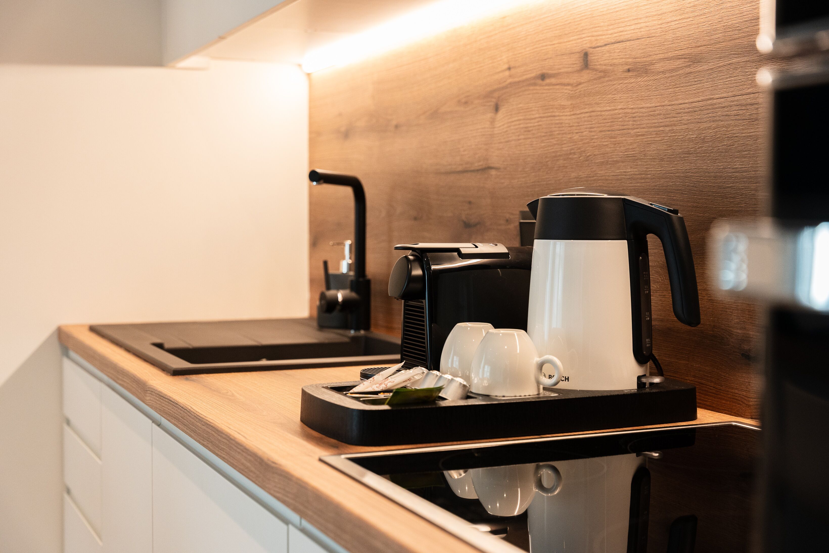 Eine moderne Küche mit integrierter Espressomaschine, einer Kaffeemaschine und einer Schale mit Tassen und einem kleinen Teller.