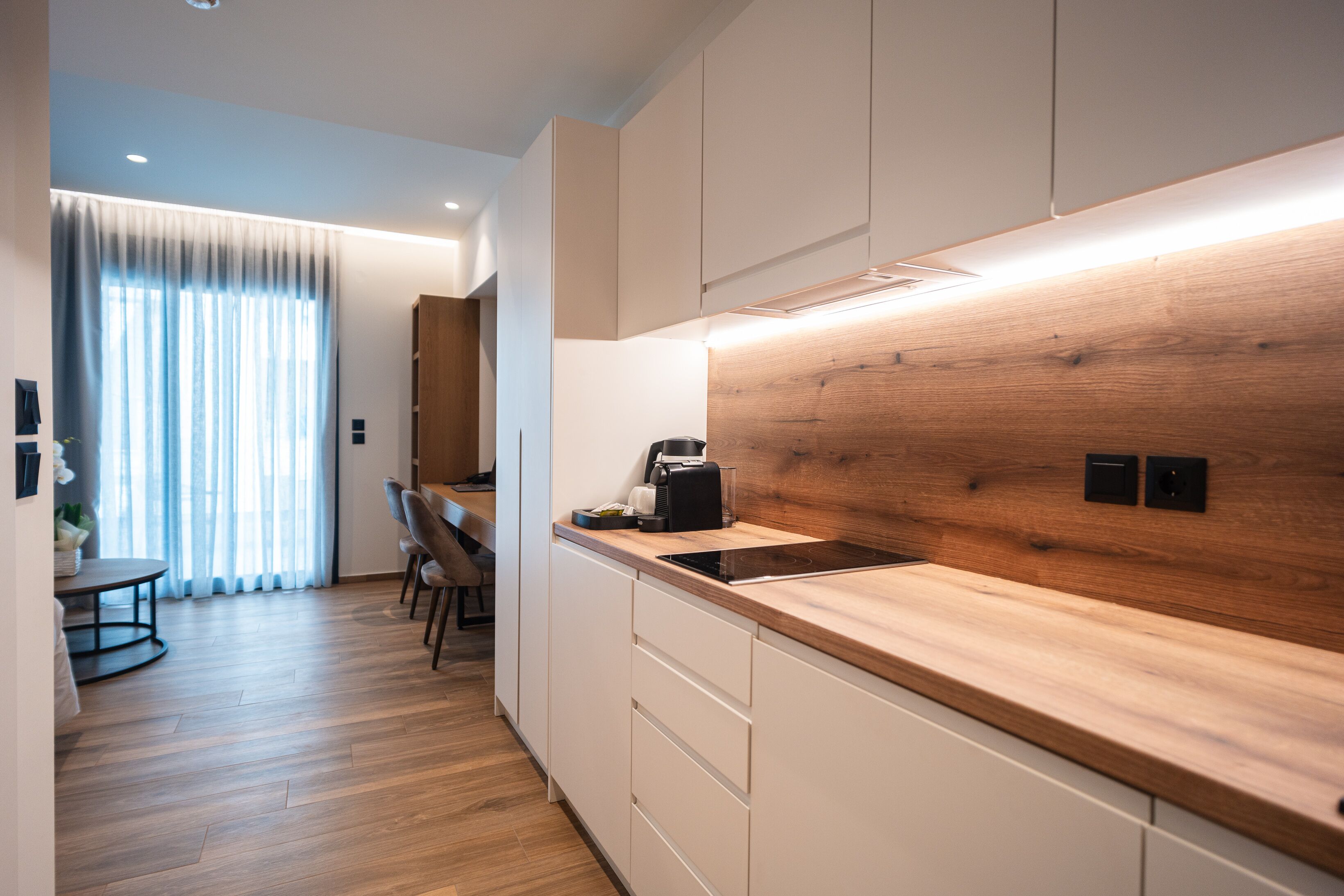 Een moderne keuken met houten aanrechtbladen, een inbouwfornuis en witte kasten.