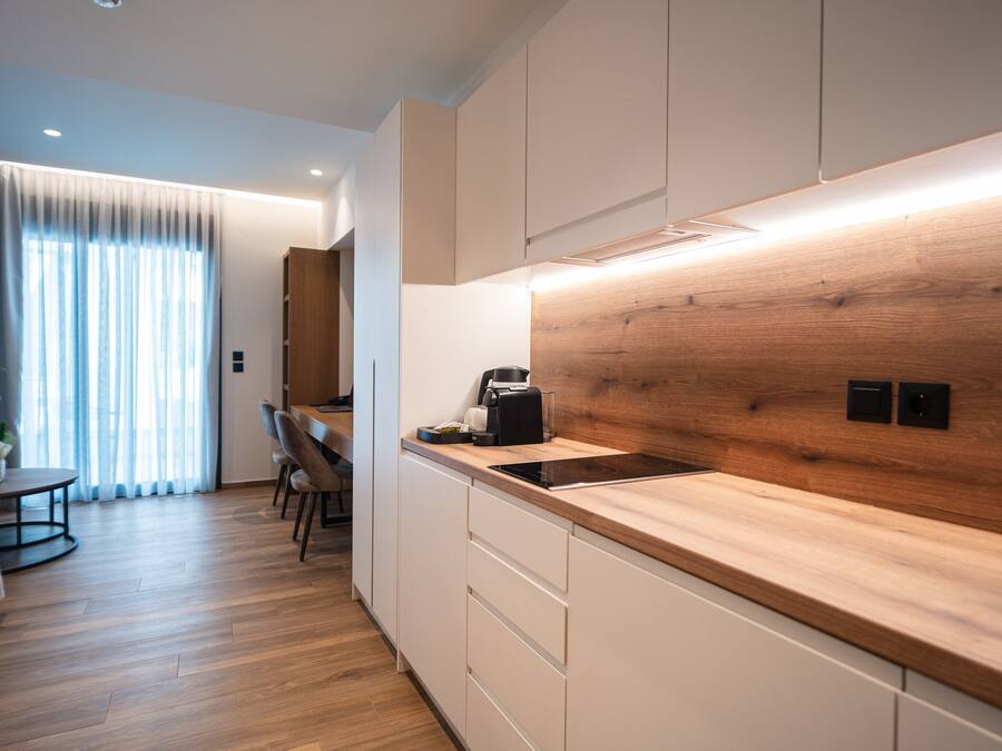 Een moderne keuken met houten aanrechtbladen, een inbouwfornuis en witte kasten.