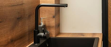 Una cocina moderna con un lavamanos negro, encimera de madera y grifo negro.