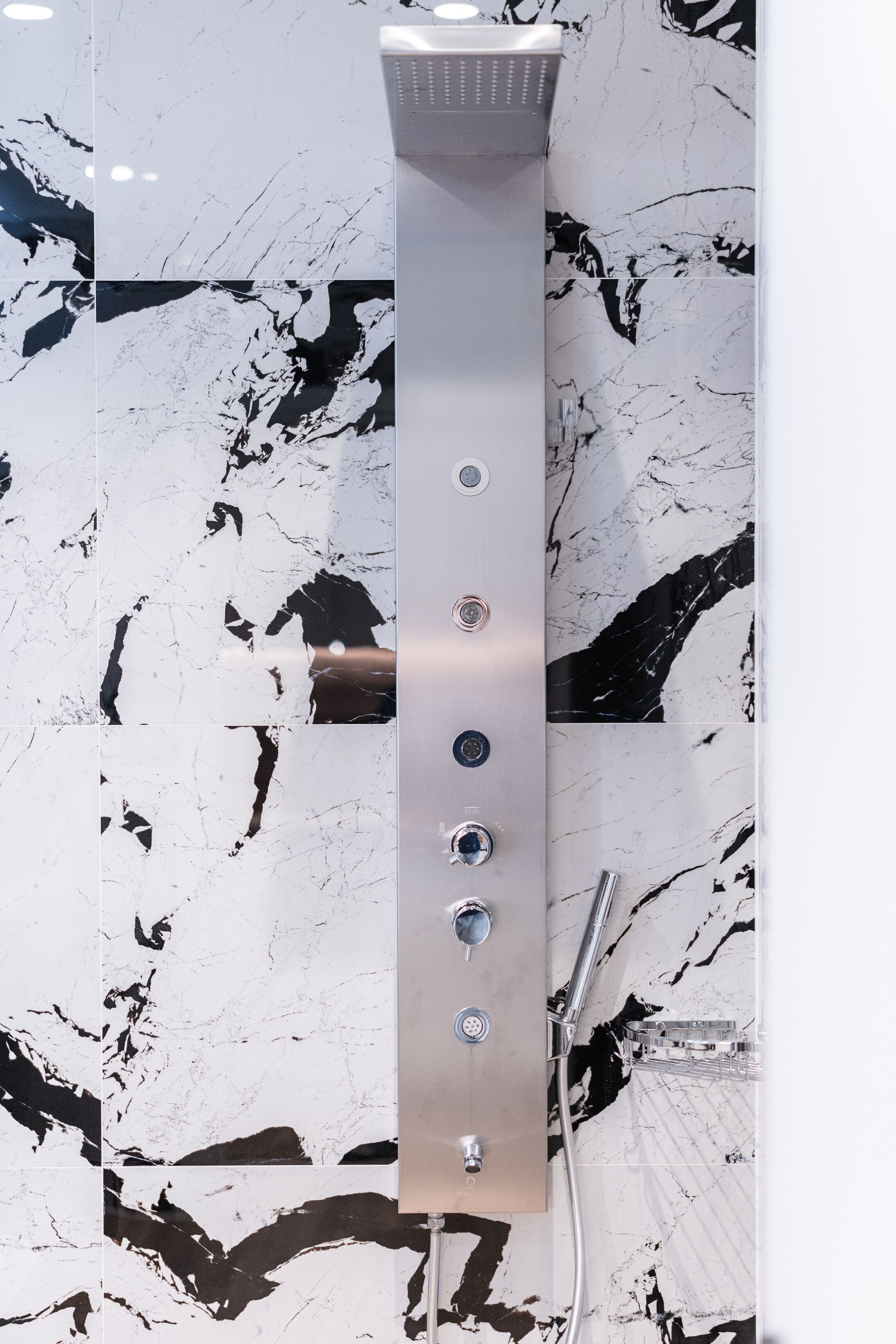 A modern shower with a sleek, metallic design and multiple control knobs.