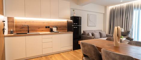A modern kitchen with white cabinets, a wooden countertop, and a black refrigerator.