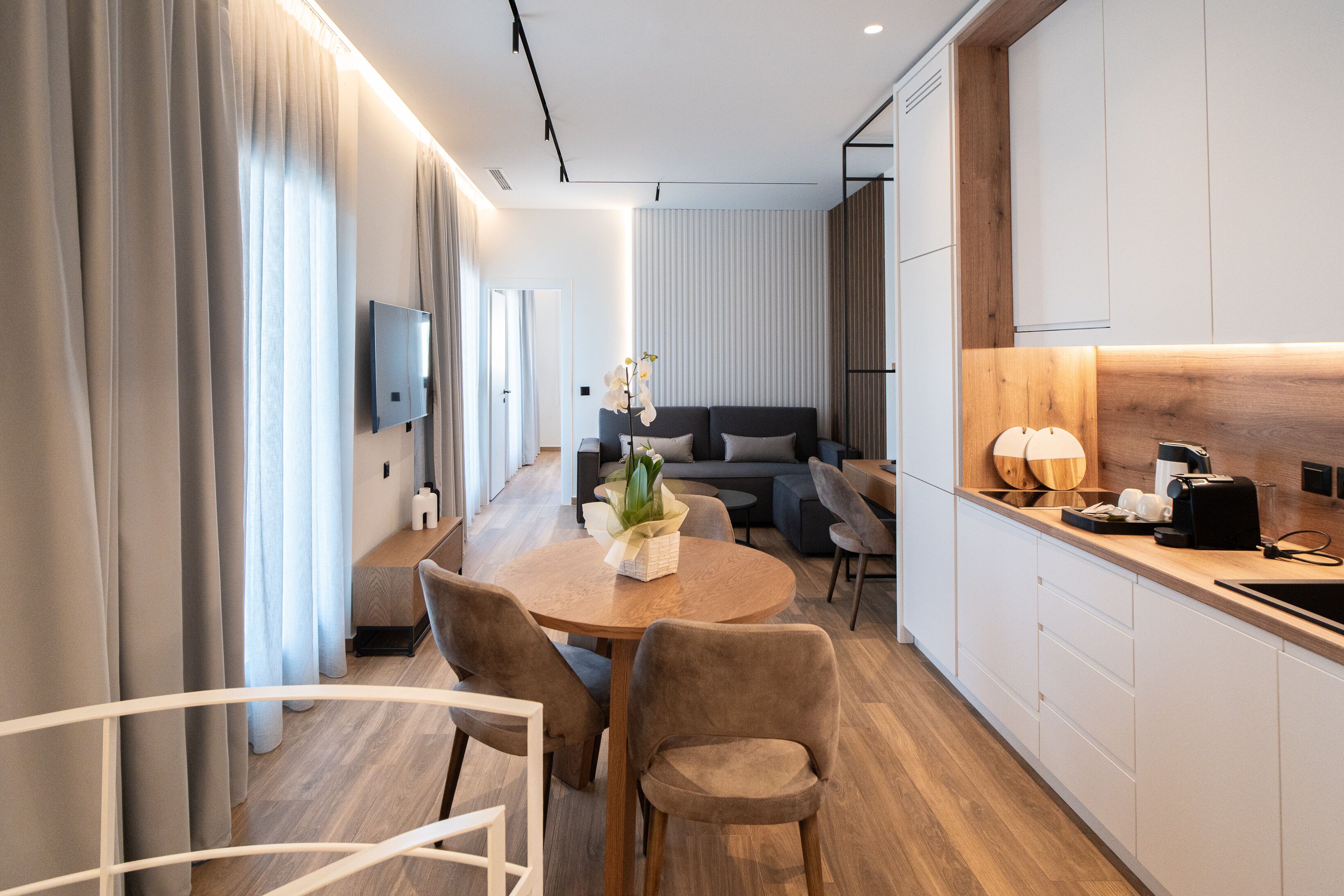 Ein modernes Hotelzimmer mit Essbereich, einer Couch und einer Küchenzeile.
