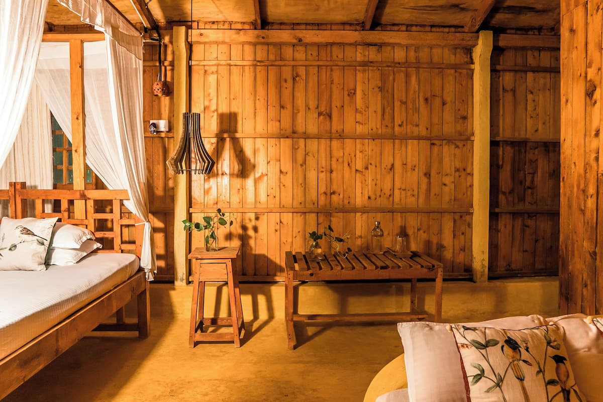 Una stanza in legno con un letto, una panca e un tavolino.