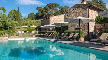 Una piscina al aire libre de temporada, sombrillas