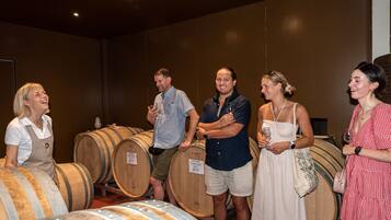 A group of people standing in a room with wooden barrels, likely a wine cellar or tasting room.