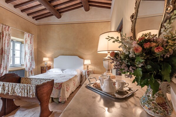 A hotel room with a wooden bed, two bedside tables with lamps, a large mirror, and a tray with tea set. - Tenuta Guardastelle (San Gimignano)
