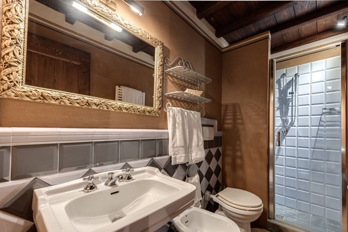 A bathroom with a large mirror, a sink, a toilet, and a shower.