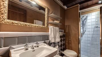 A bathroom with a large mirror, a sink, a toilet, and a shower.