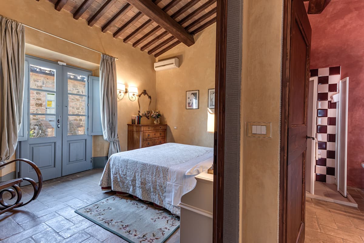 A bedroom with a bed, a dresser, a mirror, and a door leading to another room.