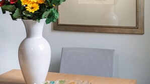 A framed portrait on a wall, a white vase with flowers, and a table with a glass bowl. - House on the Roof - Florence Dolce Vita (Firenze)