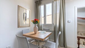 A dining area with a wooden table, grey chairs, a vase with flowers, and a framed picture on the wall. - House on the Roof - Florence Dolce Vita (Firenze)