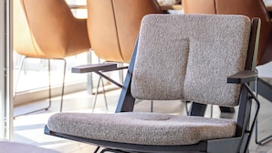 Un interior moderno con una silla estampada, una mesa redonda y vistas al exterior.
