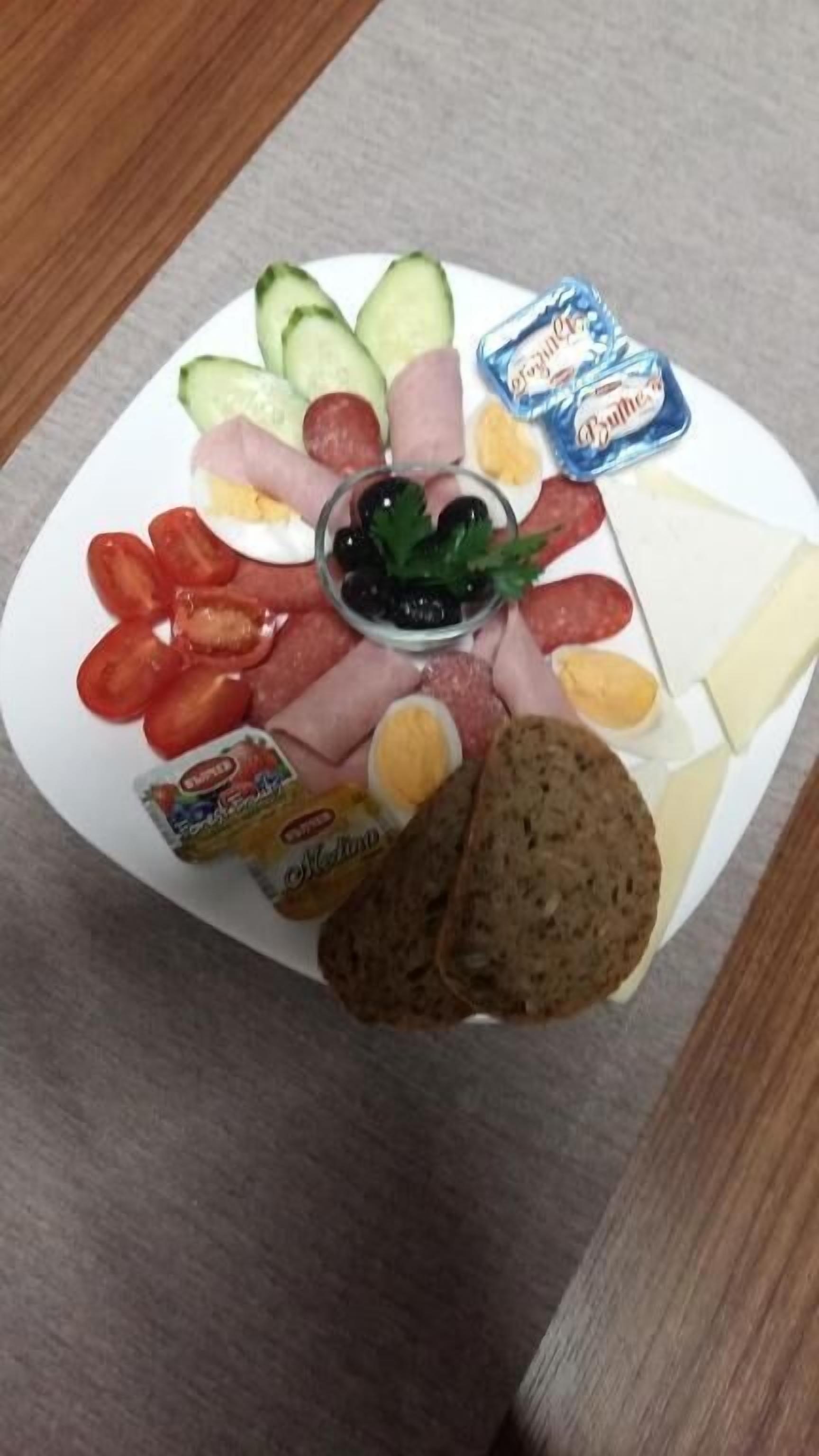 Ein Teller mit verschiedenen Speisen, darunter Gurken, Tomaten, Eier, Käse und Brot.