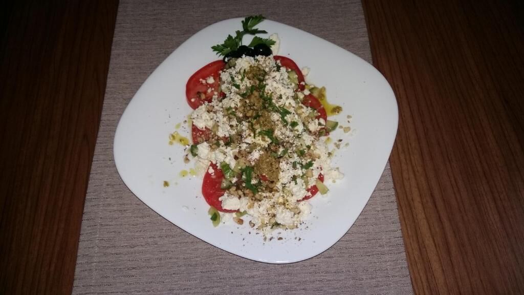Un plat blanc amb un plat de menjà a taula de fusta.