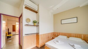 A bedroom with a wooden bed, a bedside table, a wall-mounted shelf with decorative items, and a door leading to another room. - Nice little townhouse Bordeaux (Bordeaux)