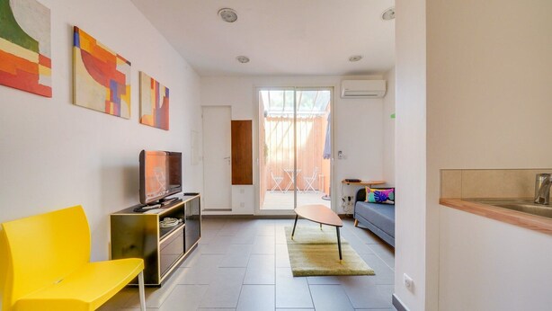 A modern living room with a TV, yellow chair, and artwork on the wall. - Nice little townhouse Bordeaux (Bordeaux)