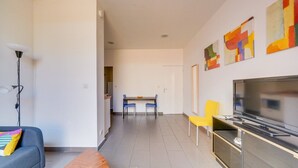 A modern living room with a sofa, a TV, and a dining area with chairs and a table. - Nice little townhouse Bordeaux (Bordeaux)