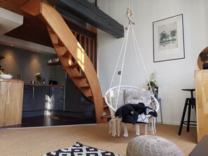 A modern interior with a wooden staircase, a hanging chair, and a kitchen area. - Bright, Beautiful Flat in Central Bordeaux (Bordeaux)
