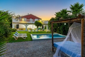 A pool area with lounge chairs, a bed with a canopy, and a building with a balcony. - Fidalsa Divine Hiding (Algorfa)